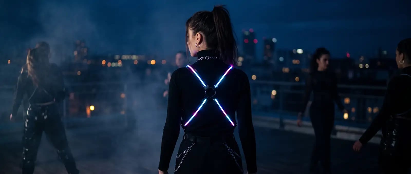 Frau von hinten auf Rooftop mit LED-Harness